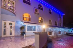 Un edificio blanco con un coche aparcado delante. en Márvány Panzió, en Hajdúszoboszló