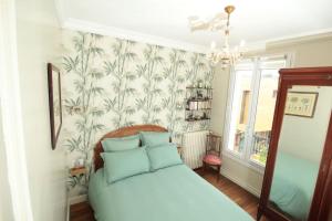 a bedroom with a white bed with blue pillows at Villa années 30, bords de Marne in Joinville-le-Pont