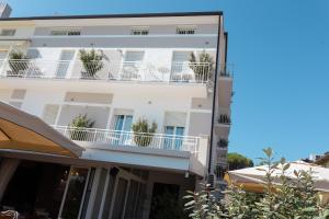 a white building with potted plants on the balconies at Hotel Ronchi in Cervia