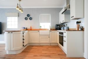 a kitchen with white cabinets and a wooden floor at Fabulous 3-bedroom home across St Michaels Mount in Marazion