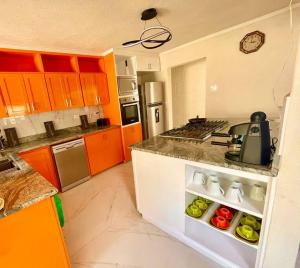Una cocina con gabinetes de color naranja y una encimera con una tetera. en Barbados Exotic luxury living, en Christ Church