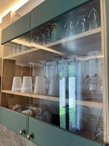 a glass cabinet with dishes and glasses on it at La maison RayoFam, à 30 min de Paris, à 5 min du stade de France in Saint-Denis +46 photos