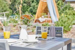 a table with a vase and two glasses of orange juice at Strandglück Prerow in Prerow