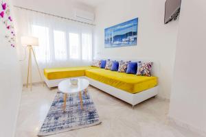 a living room with a yellow couch and a table at Ilion Luxury Apartments in Asprovalta
