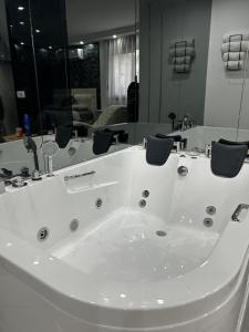 a large white tub in a bathroom with mirrors at Love spa apartman in Banja Koviljača +44 photos