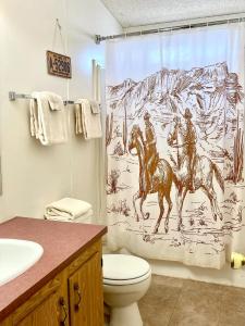 a bathroom with a shower curtain with two men riding horses at Lee's Ferry Lodge at Vermilion Cliffs in Marble Canyon +179 photos