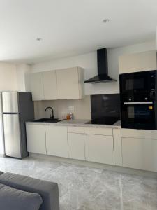 a kitchen with white cabinets and a stainless steel refrigerator at Superbe villa familiale jardin in Montpellier