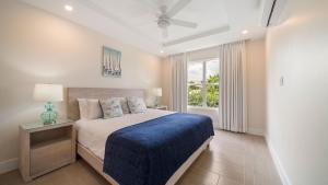 a bedroom with a bed with a blue blanket and a window at Coral Beach 202 condo in Saint Peter +12 photos
