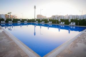 a large swimming pool with chairs and blue water at Zephyr Agadir in Agadir