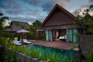 a villa with a swimming pool and a house at Sanctoo Suites & Villas in Sukawati