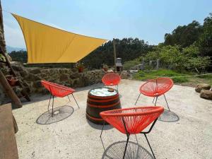 eine Gruppe roter Stühle und ein Fass in der Unterkunft CASA ViLLAR in Colunga