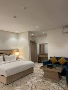 a bedroom with a bed and a blue couch at ليبرا سويتس - Libra Suites in Khamis Mushayt