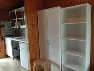 a kitchen with white cupboards and a stool at Domki 13-nastka in Międzyzdroje