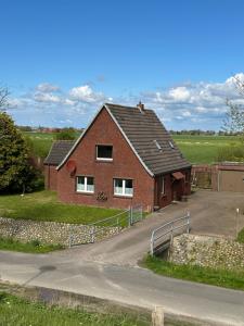 a red brick house with a fence next to a road at Ferienhaus-DeichBrand in Friedrichskoog
