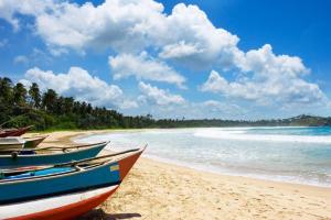 two boats sitting on a beach next to the ocean at Eleven Thalalla in Talalla South