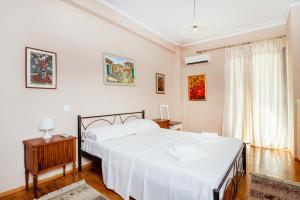 a bedroom with a large white bed and a window at Charming & Authentic Gem - Walk to Port & Shops! in Patra