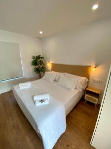 a bedroom with a white bed with two towels on it at La Santillana Luxury Apartments in Santillana del Mar