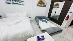 a white bedroom with two beds and a table at Olivz Residence Furnished Cozy Studio Apartment in Dubai +29 photos