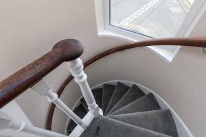 a spiral staircase with a wooden rail and a window at Lighthouse Cottage Unique Apartments in Scarborough
