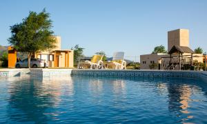 a swimming pool with chairs and chairs next to a house at Roena Cabañas in Villa Giardino