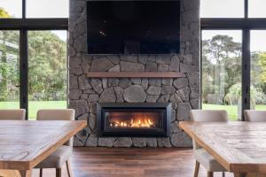 a fireplace in a room with two tables and chairs at Kaitahi Lodge in Palmerston North
