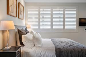 a bedroom with a bed with white pillows and a window at Kaitahi Lodge in Palmerston North