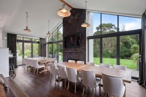 a dining room with a table and chairs and large windows at Kaitahi Lodge in Palmerston North