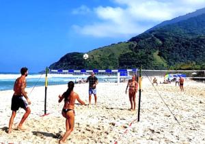 a group of people playing volleyball on a beach at Apartamento Vista ao Mar Maresias in Maresias