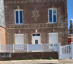 a brick building with a white fence in front of it at Apparemment T2 en centre ville in Gournay-en-Bray