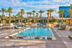 a hotel pool with palm trees and chairs at Mgm Balcony Strip Sphere And F1 Race Views Suite in Las Vegas