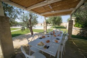 Castrignano deʼ GreciにあるLisària Villa Delle Meraviglie With Poolの木製屋根の下に白い椅子が置かれた長い白いテーブル