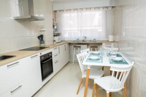a white kitchen with a table and chairs at Home Ourense Miño in Ourense