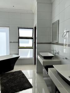 a white bathroom with two sinks and a tub at Hidden Gem in Centurion