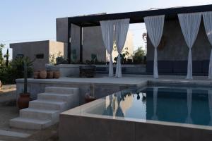 una casa con una piscina con cortinas blancas en Casa Michaus Valle de Guadalupe, en Valle de Guadalupe