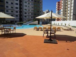 a pool with tables and chairs and umbrellas in a courtyard at Riviera Park in Caldas Novas