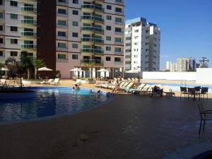 a swimming pool with people in the water and buildings at Riviera Park in Caldas Novas