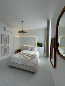 Un dormitorio blanco con una cama y un espejo. en Capsule ciné glisse - cinéma - spa balnéo - garage, en Roubaix
