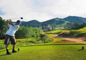 een man zwaaiend met een golfclub op een golfbaan bij Red Pine Mountain Retreat steps from the Cabriolet in Park City