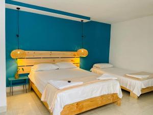 two beds in a room with a blue wall at Hotel Neblina Calima in Calima
