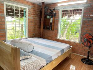 um quarto com uma cama grande numa parede de tijolos em Ty Phu Miet Vuon Homestay - Entire Bungalow em Tây Ninh