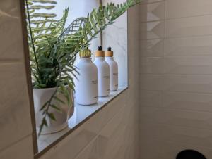 a row of white bottles sitting on a shelf in a bathroom at Charming Clovis Retreat Central Location Modern Amenities Cozy Style in Clovis