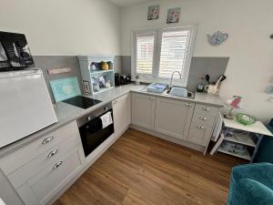 a kitchen with white cabinets and a sink at 33B South Shore Village in Bridlington