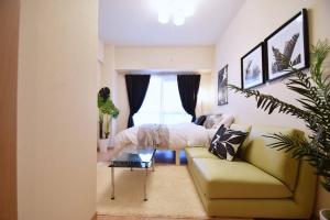 un soggiorno con un divano e un letto di カモミール西町 203 a Kume