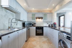 a kitchen with white cabinets and a sink and a dishwasher at Luxury Beachfront 706 with AC, Workspace & Table Mountain Views in Cape Town