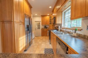 a kitchen with wooden cabinets and a stainless steel refrigerator at Parkside Escape South Hill w Private ADU in Spokane