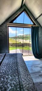 a bedroom with a large window with a view of a field at Shahdag Mountain House in Qusar