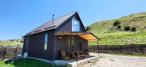 a black tiny house with a picnic table in front of a hill at Shahdag Mountain House in Qusar