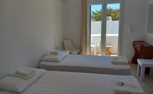 two beds in a white room with a window at Naias in Livadi