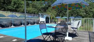 two chairs and an umbrella next to a swimming pool at Hameau les Combelles in Martel