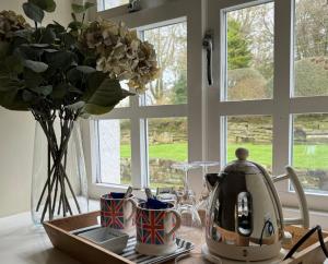 a kitchen table with a tea kettle and a vase with flowers at South Craighall B&B in Eaglesham